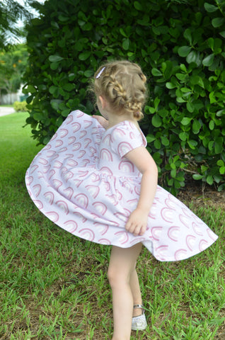 young girl in double braid twirling in rainbow print dress