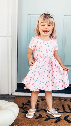 young girl in front of blue door with polka dot twirl dress