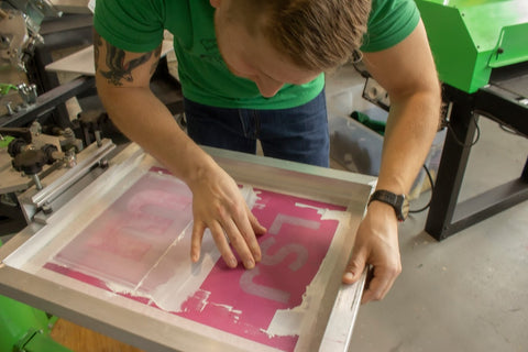 Carefully aligning the screen with ink so it can be printed properly. 