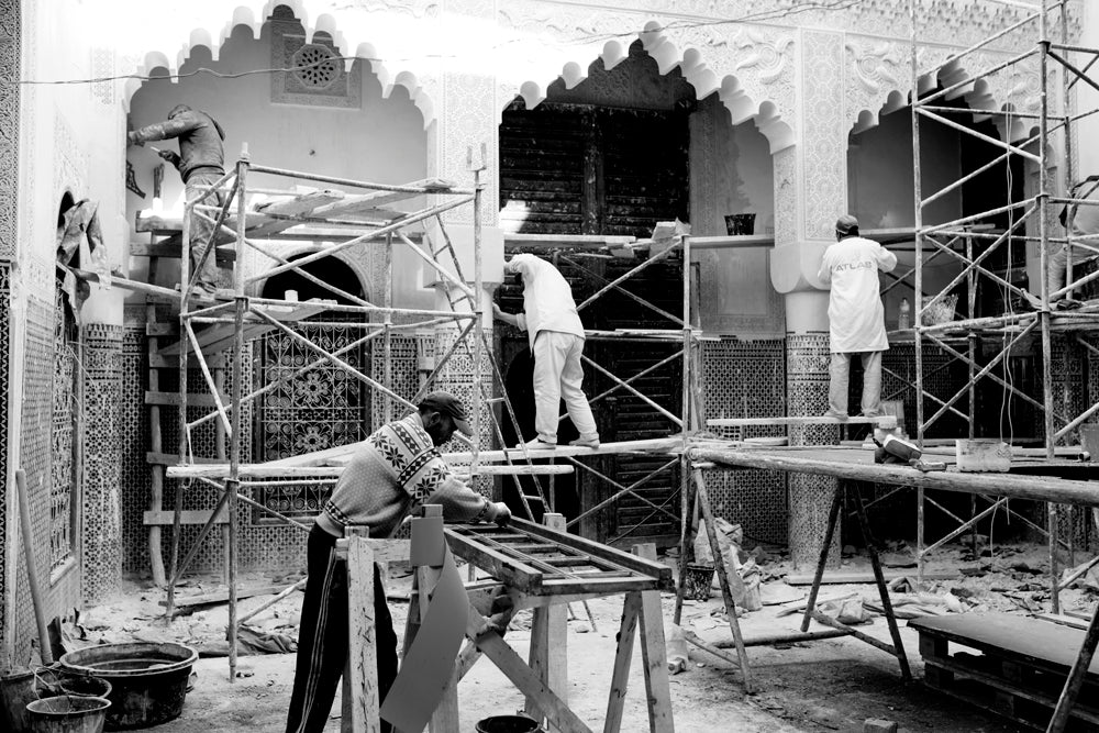 Four masonry workers stand on scaffolding while working to restore a home (traditional: riad).  Fez, Morocco.