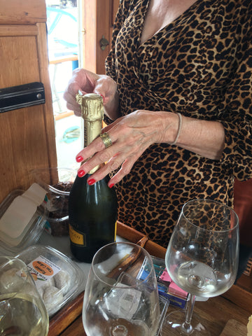 woman popping open champagne with red manicure and leopard dress