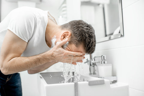 man scrubbing face with scrub
