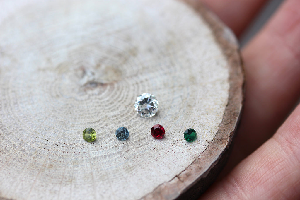 Clients gems removed from ring sitting on table, Larger diamond, four smaller stones in blue, yellow, red and green