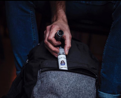 man putting vape juice and pen into backpack