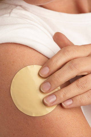 woman placing nicotine patch on arm