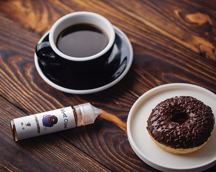 a cup of coffee, a donut, and a bottle of premium Velvet Cloud e-liquid