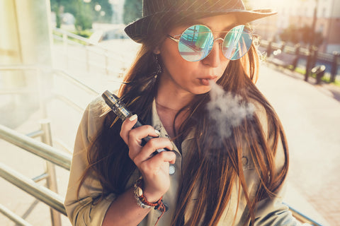 young woman holding vape mod surrounded by vape cloud