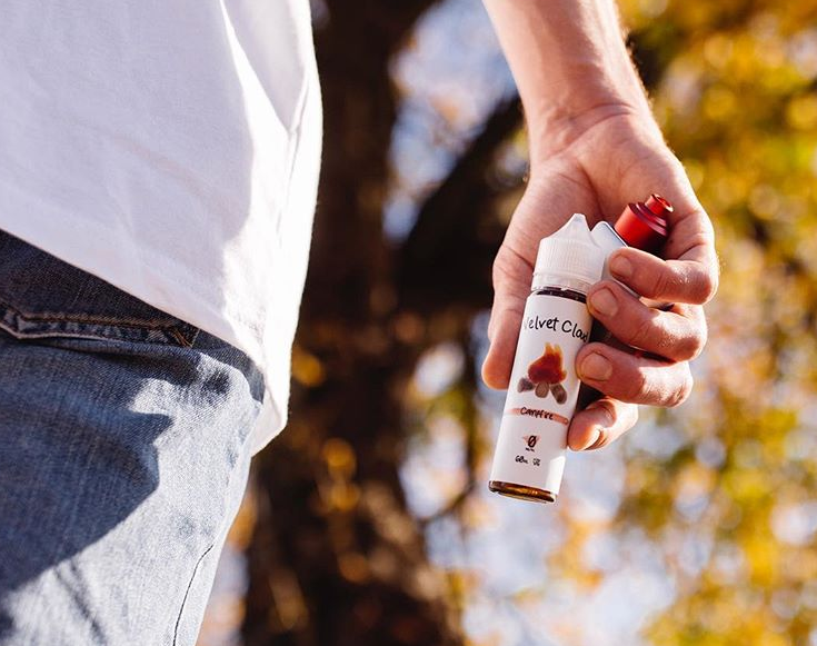 a man holding a bottle of dessert-flavored e-liquid on a fall day