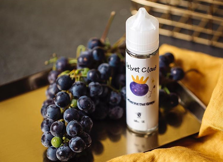 an image of grapes and Velvet Cloud grape-flavored e-liquid on a yellow tablecloth