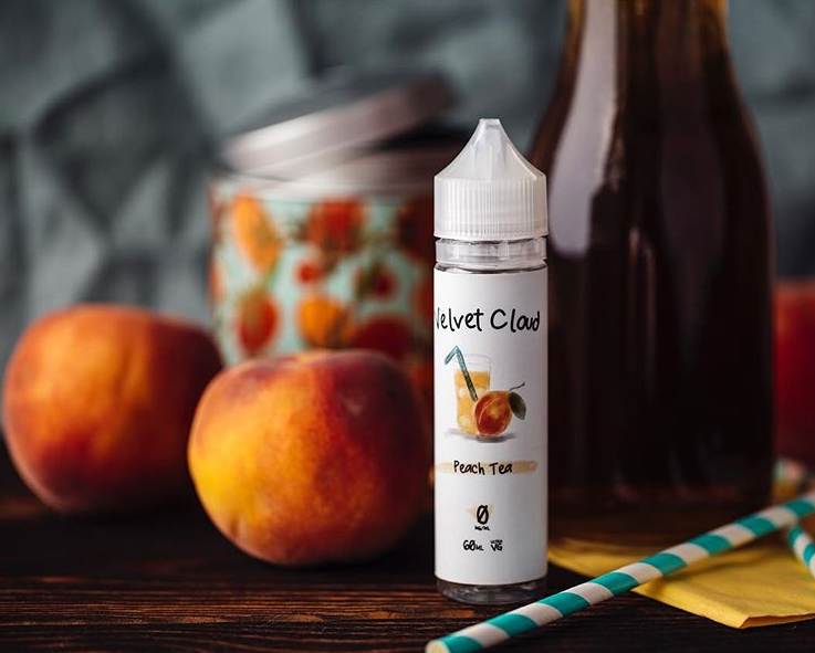 a picture of peaches and Velvet Cloud peach-flavored e-liquid on a picnic table
