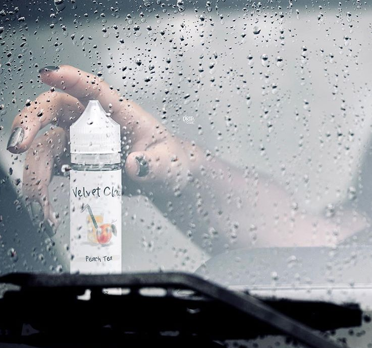 woman reaching for a bottle of peach flavored Velvet Cloud e-liquid on a rainy day