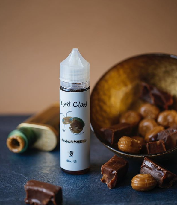 Velvet Cloud Mewlew's Magic e-liquid on a table next to caramels and chocolates