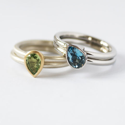 A bespoke and contemporary set of engagement rings in platinum with an aquamarine, and in white and yellow gold with a mint garnet. Made to commission