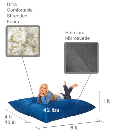The 6 ft Bean Bag Pillow in royal blue with a smiling girl relaxing on it. Labels are indicating that it is made of shredded foam and has a microsuede cover. There are measurements shown that say it is 6 feet long, 4 feet and 10 inches wide, 1 foot high, and weighs 42 pounds.