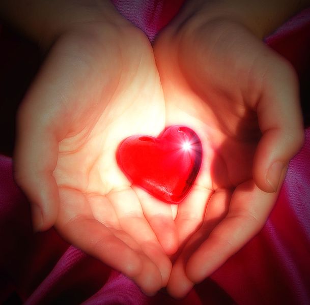 Red, glowing, heart-shaped stone held by two hands