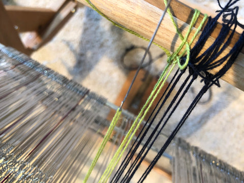 pulling the yarn through the heddle