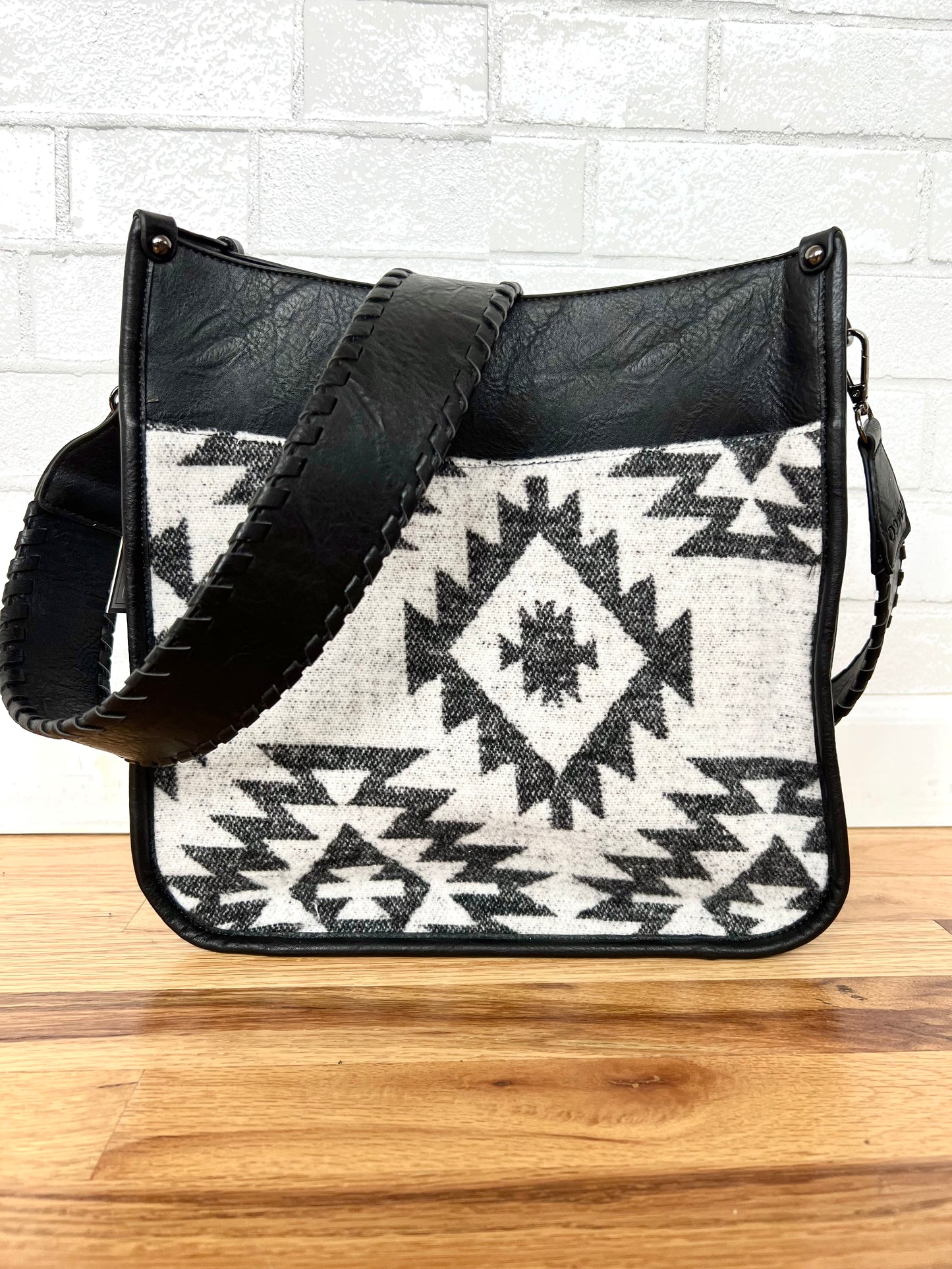 Crossbody with aztec print on the front and leather on the top and the strap. 12”x12”x3 1/2”