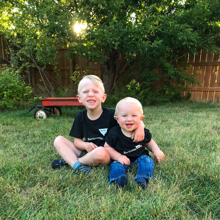 two young kids smiling in black earthetarian shirts