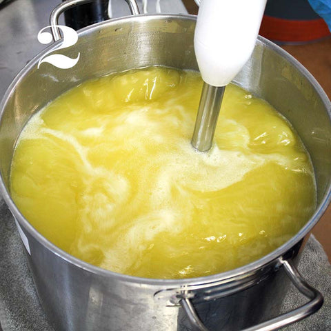 An immersion blender mixes a yellow-hued liquid