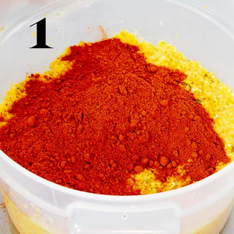 Red powder and a chopped yellow mixture in a tub