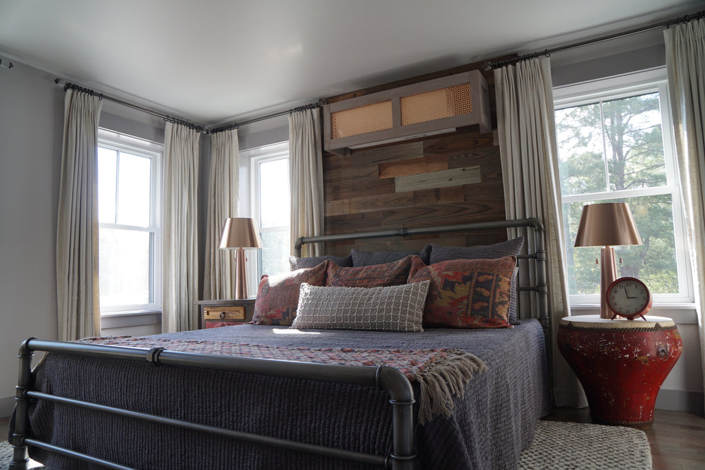 A custom DIY reclaimed headboard that reaches from floor to ceiling is attached to the wall behind the bed.