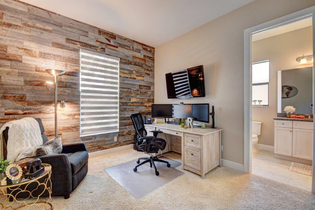 A small home office tucked in a corner that's next to a modern wood wall in a bedroom