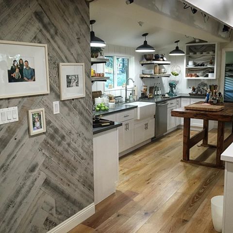Reclaimed Weathered Wood Gray interior wood plank walls done in a herringbone pattern lead the way into a kitchen.