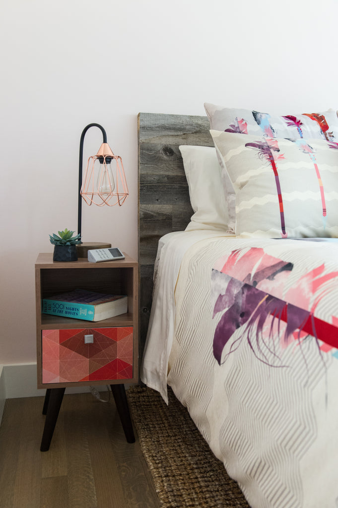 A diy reclaimed headboard has pillows piled against it in a feminine bedroom