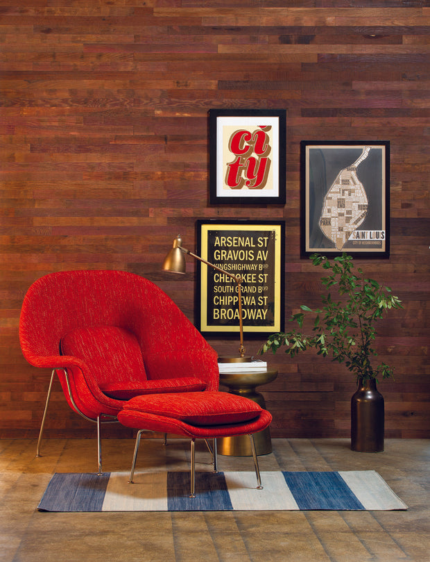 Red wine stained barnwood wall and modern red chair with metal accents add warmth to a sitting room.