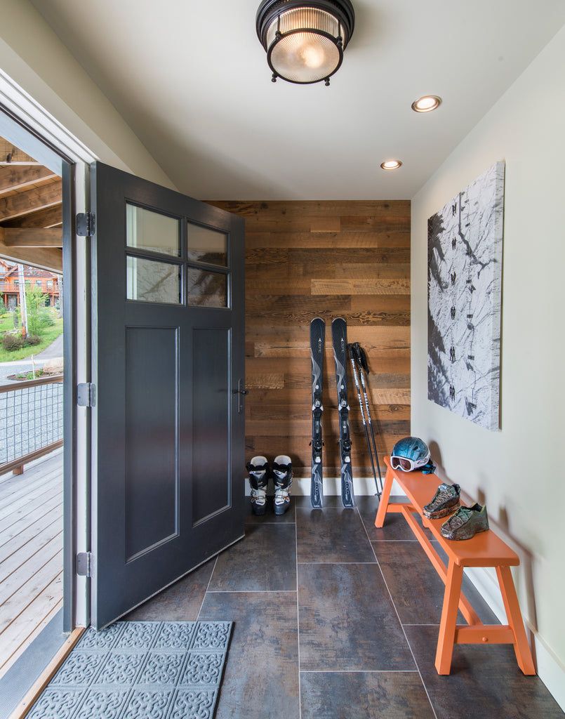 Barn wood wall paneling creates a focal wall in ski cabin foyer where skis and boots accumulate.