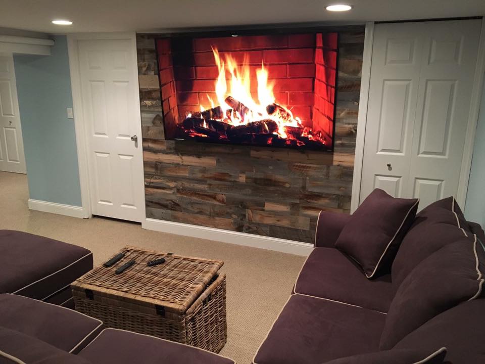 Wood plank fireplace wall with faux television fireplace hanging on it