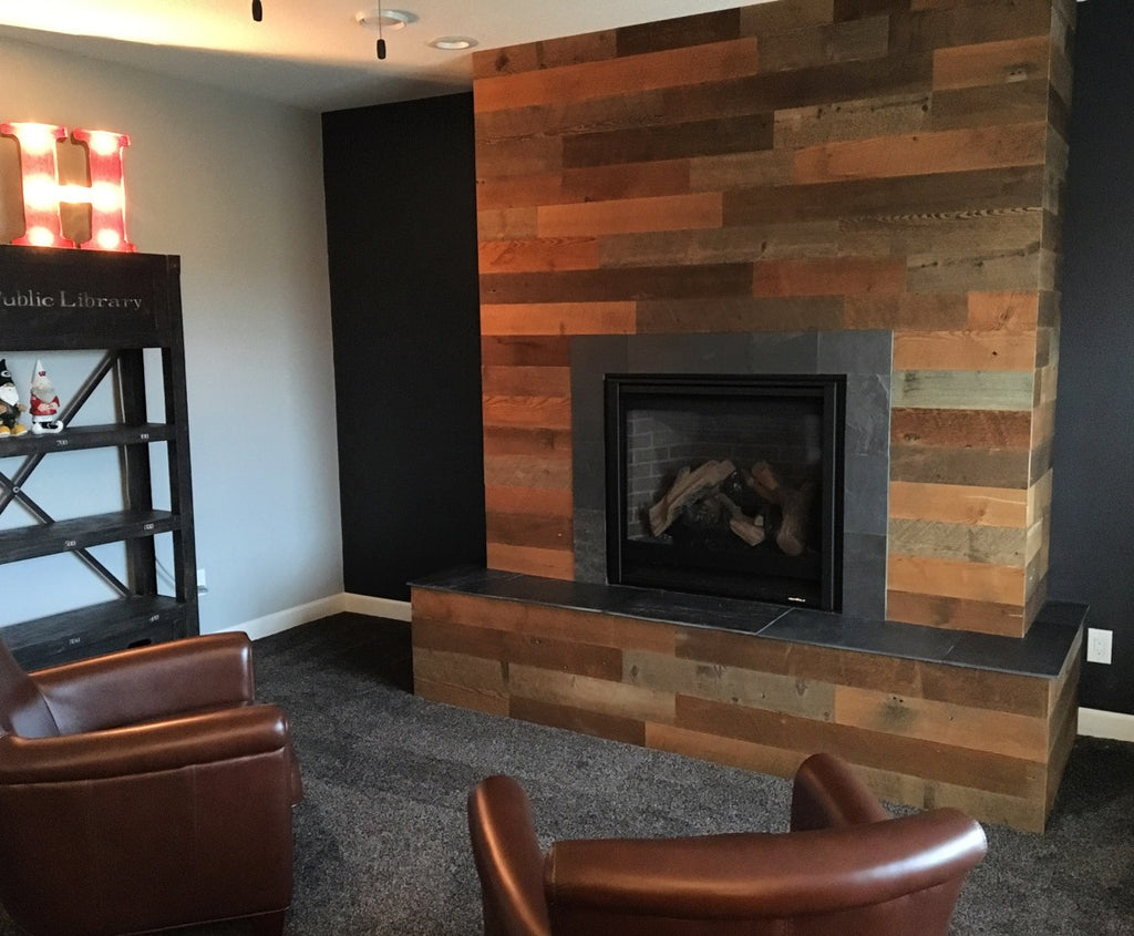 Mixed wood plank fireplace wall without a mantle surrounds wood fireplace