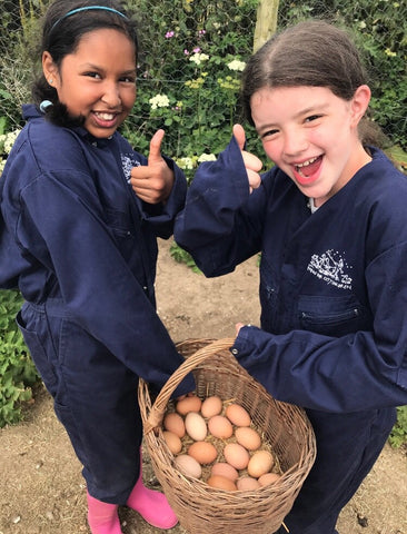 Image of two children on a Farms for City Children Farm carrying a basket of eggs