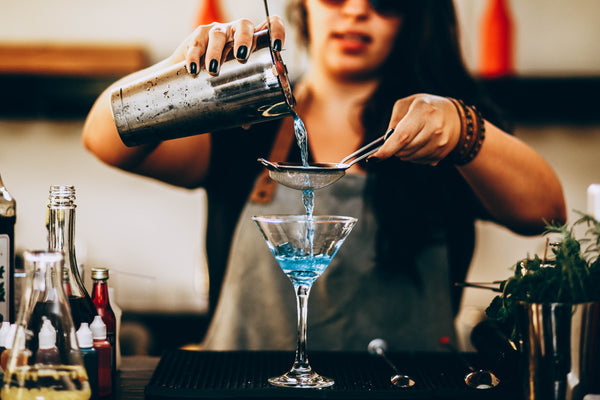 Woman making cocktail using boston shaker