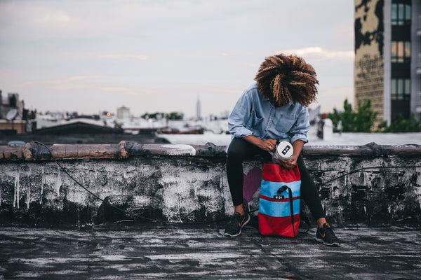 red and yellow rolltop backpack being modelled on a roof in new york city