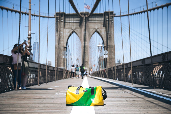 M24 yellow and green tarpaulin bag placed on the ground on the brooklyn bridge