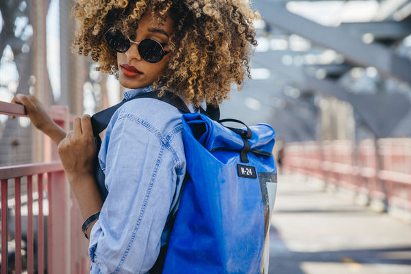 blue upcycled backpack hanging out on a bridge in new york city