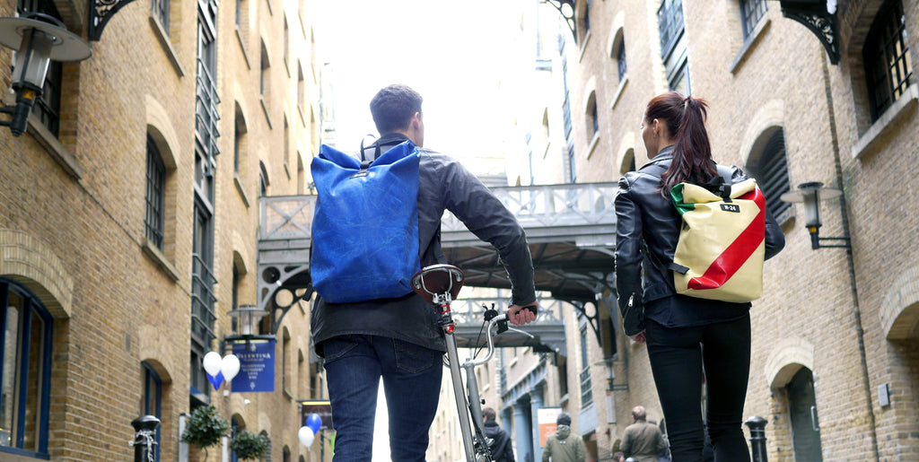 Couple walking through london bridge wearing tough lorry tarpaulins bags