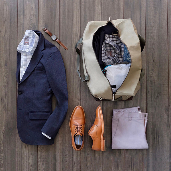 Outfit for the plane next to a duffel bag packed with our travel capsule wardrobe