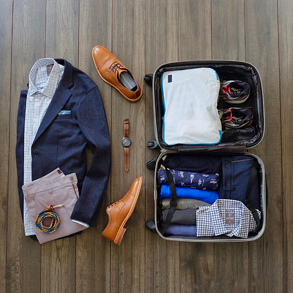 Outfit for the plane next to a rollerboard suitcase packed with our travel capsule wardrobe