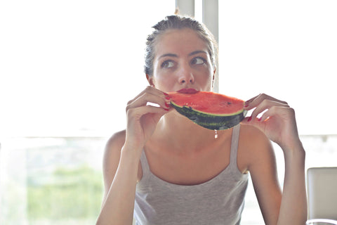 ragazza che mangia il cocomero seduta al tavolo