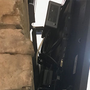Close up view of Intel NUC and external power brick mounted to back of wall mounted monitor using HIDEit VESA Adapter Bracket and Uni-XS Mounts