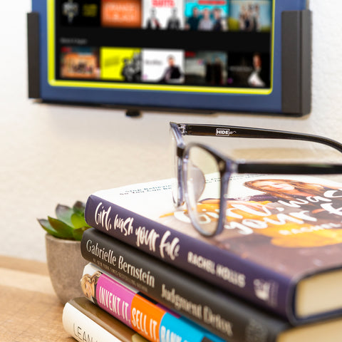 HIDEit blue light gaming glasses sitting on books with HIDEit tablet mount wall mounted