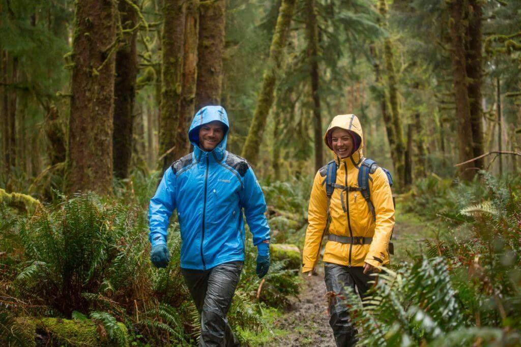 Man and Women's hiking in the rain wearing Columbia rain jackets.