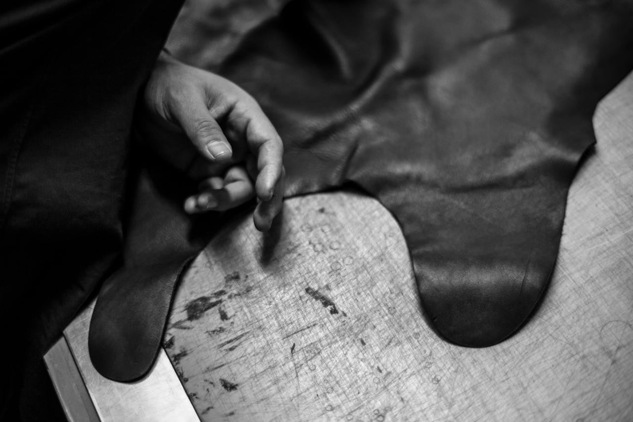 Craftsman working with high-quality black leather on a table