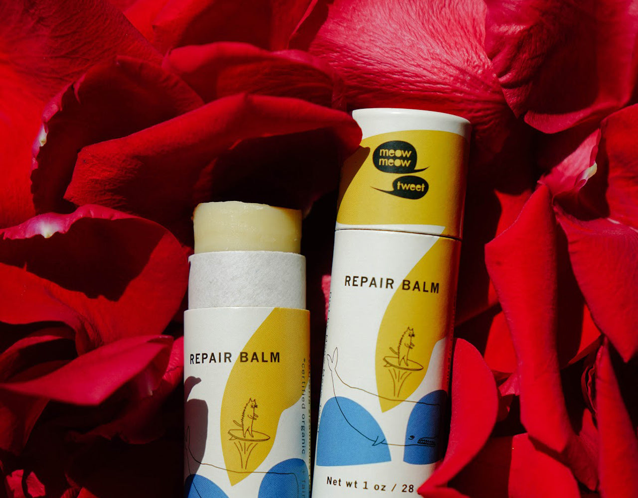 Open stick of repair balm against a background of red rose petals