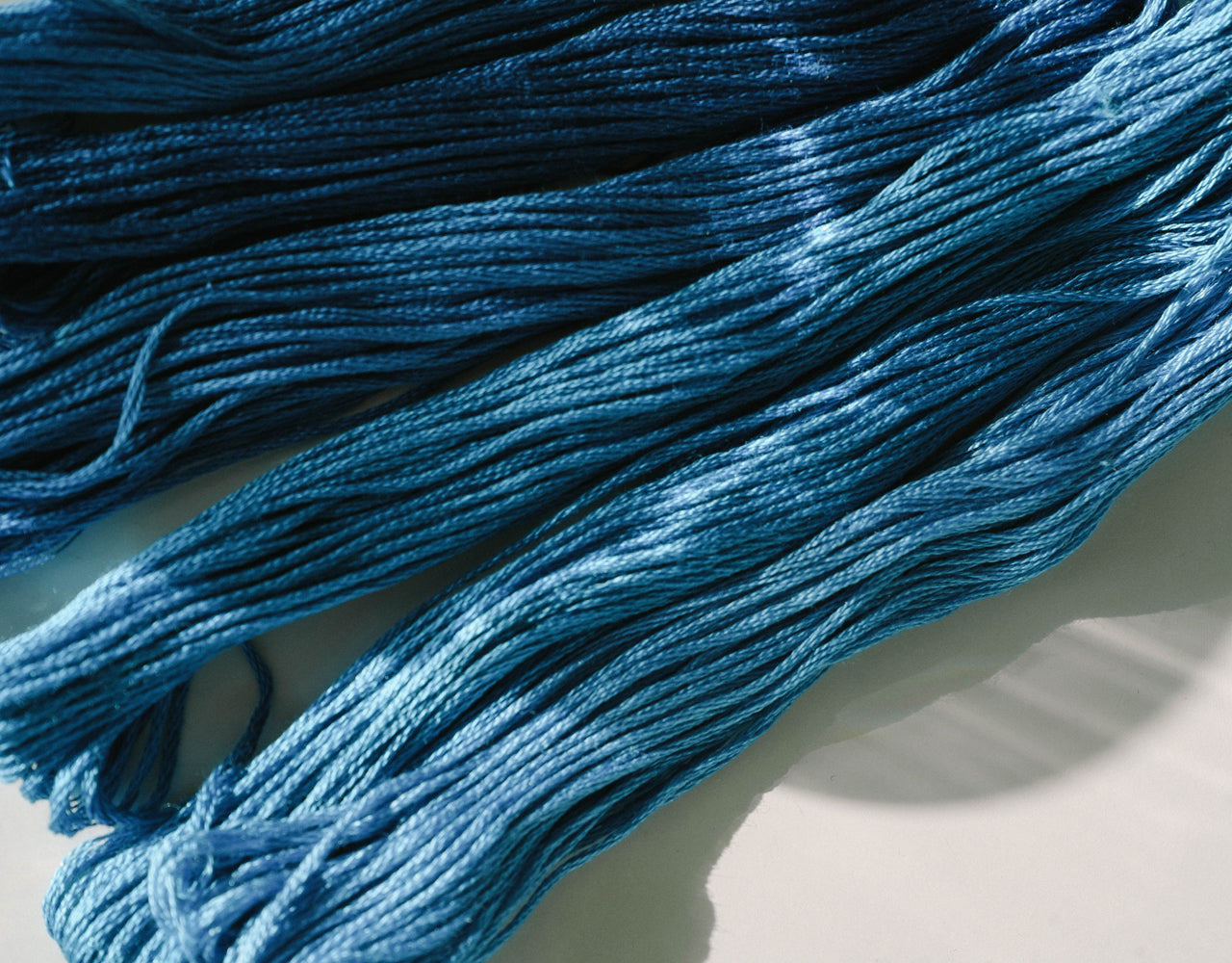 Close-up of bunches of indigo-colored cotton thread with spots of light shining on it