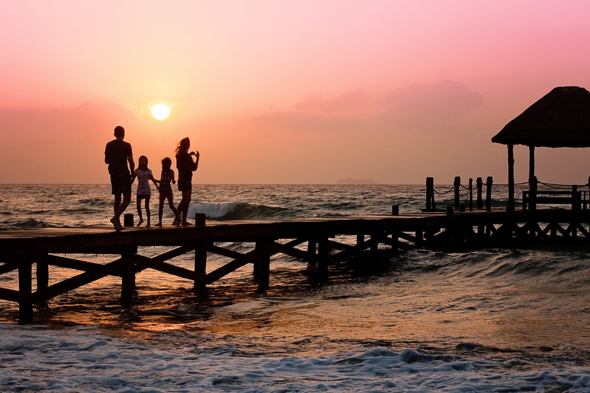 photographing silhouette of a family on a pier at sunset