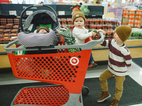kid pushing cart with baby in grocery cart hammock and car seat