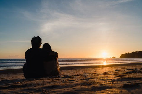 A couple on the beach at watching the sunset.